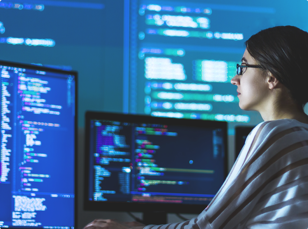 A female programmer working with multiple screens.